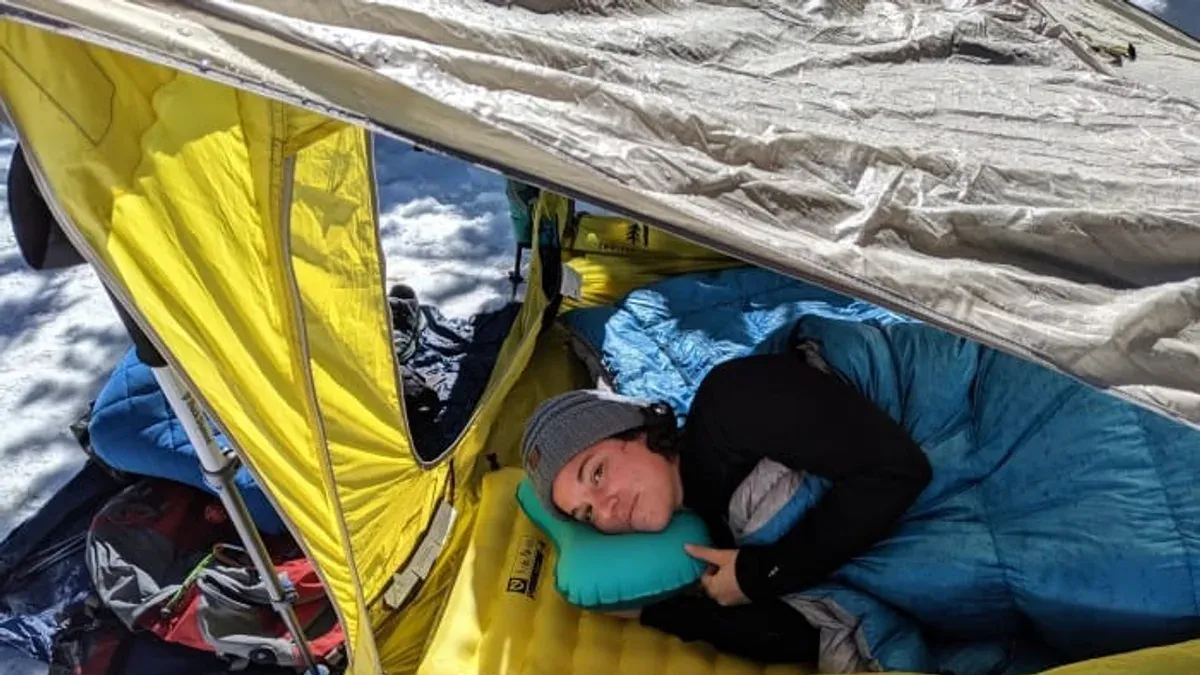 Person klär sig varmt vid ett tält under vintercamping
