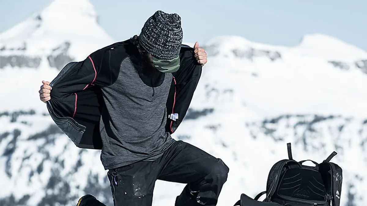 Vandrare knyter kängorna och drar på sig strumpor i merinoull på en klipphäll