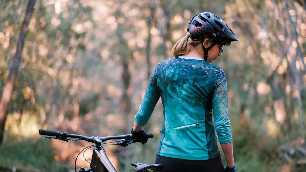 Mountainbikecyklist med hjälm leder cykeln i skogen