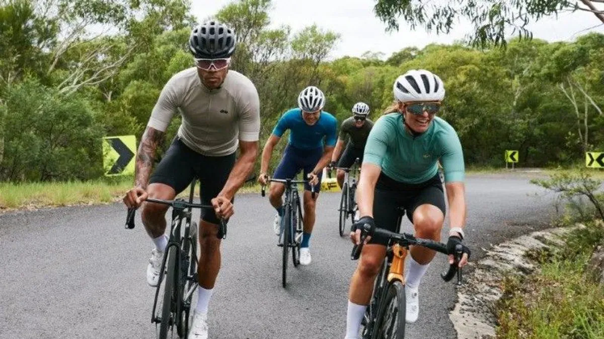 Cyklister med hjälm kör i grupp på landsväg