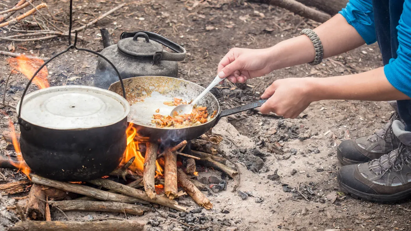 Stekpanna och kaffepanna över lägereld i skogen