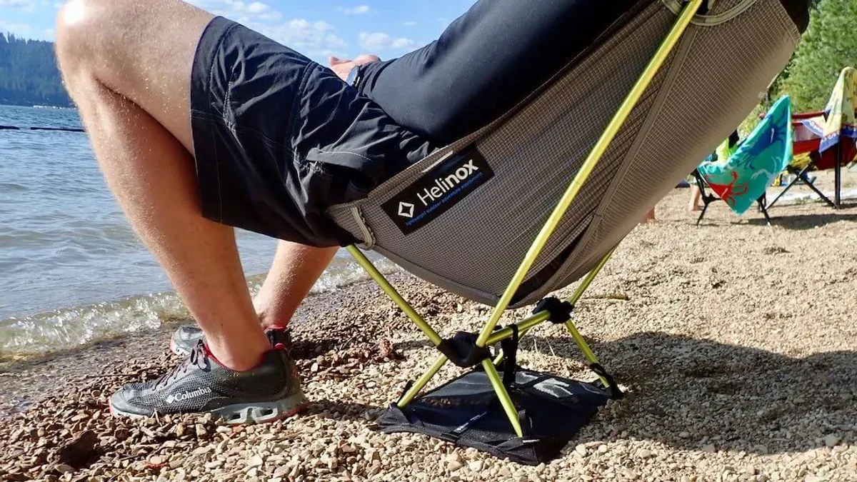 Person sitter i hopfällbar campingstol på strand