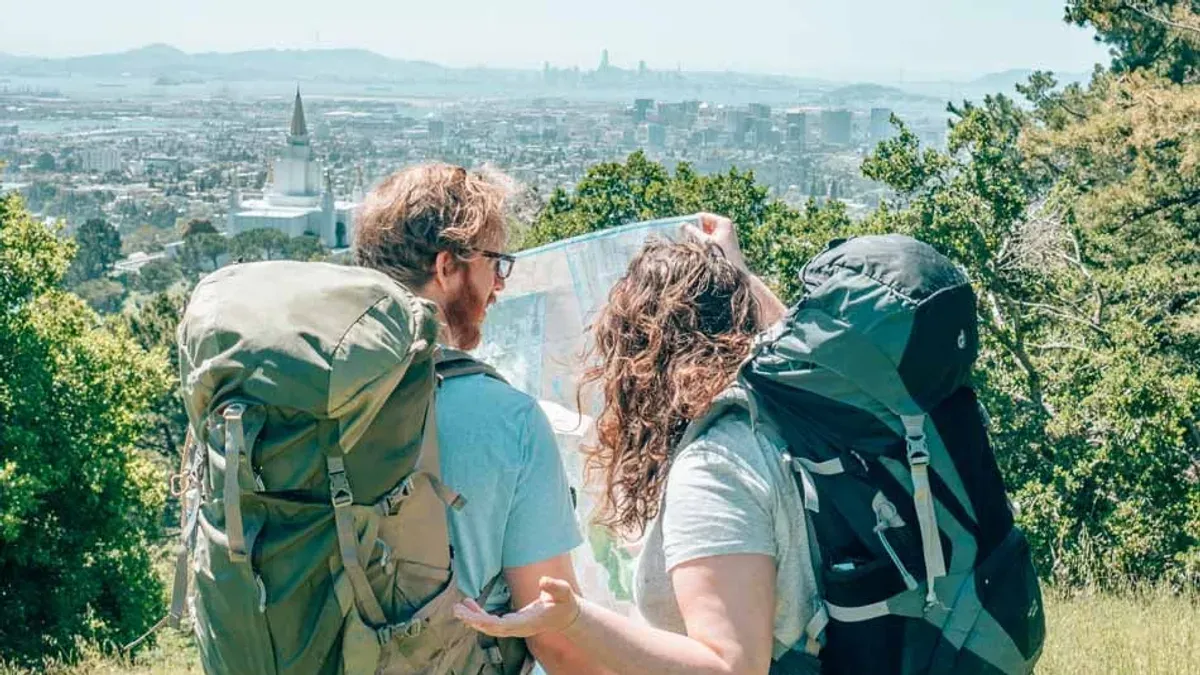 Två backpackare med ryggsäckar läser karta över stadsvy