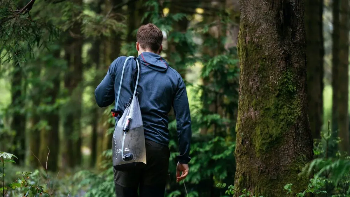 Vandrare i skog med vattenreningspåse på ryggsäcken