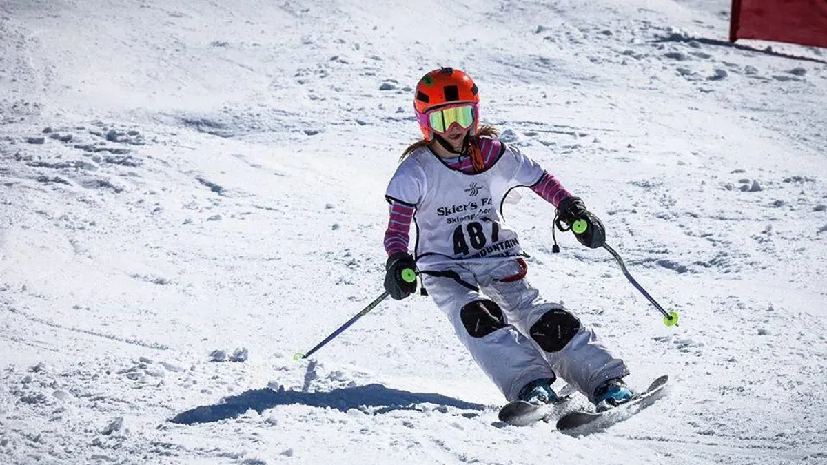 Flicka i tävlingsstartnummer åker slalom med pjäxor