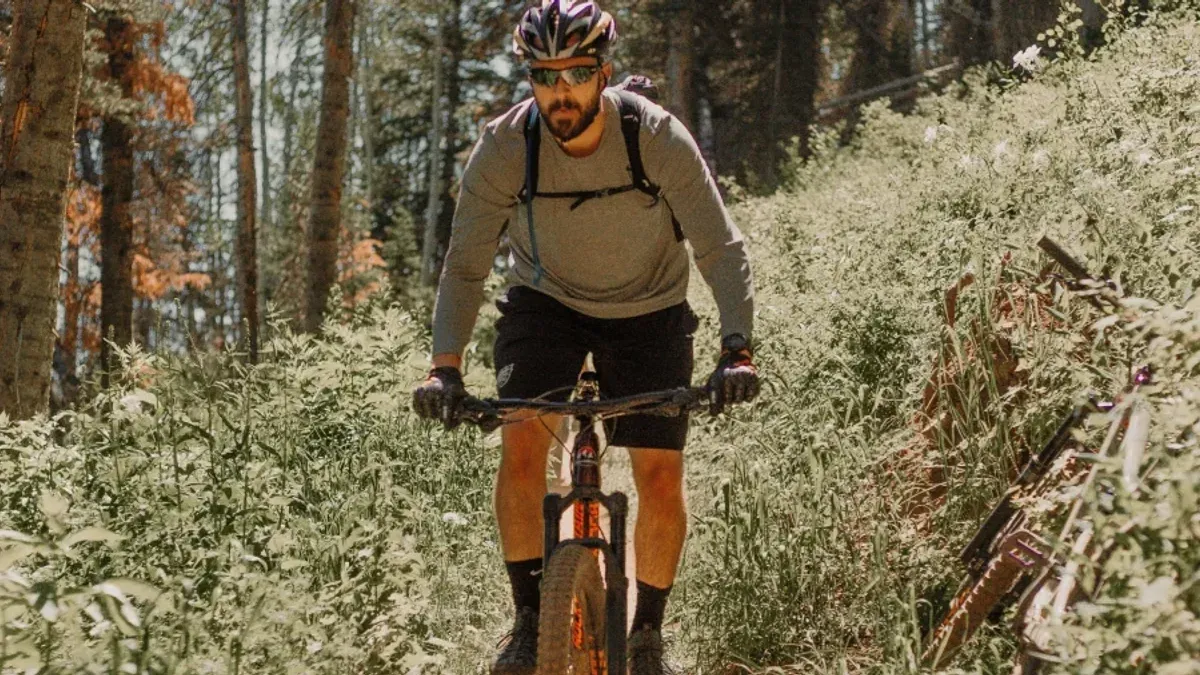 Mountainbikecyklist med ryggsäck kör på skogsstig