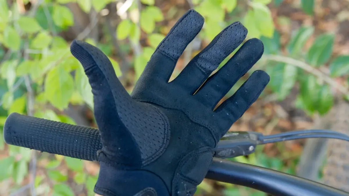 Närbild på svart cykelhandske på styre bland löv