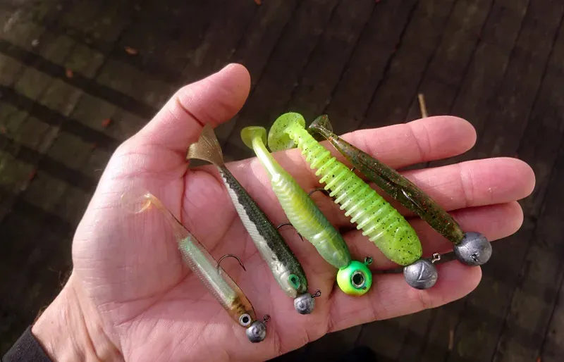 Hand håller flera färgglada fiskedrag och wobblers
