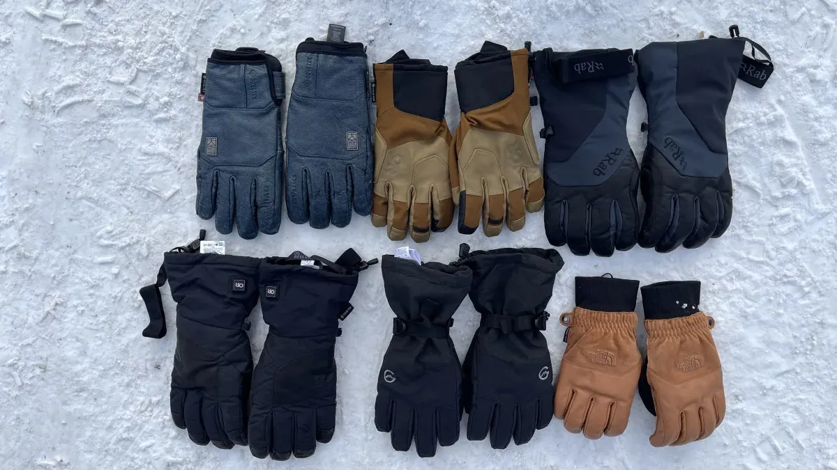 Tio par olika skidhandskar utlagda i rader på snö