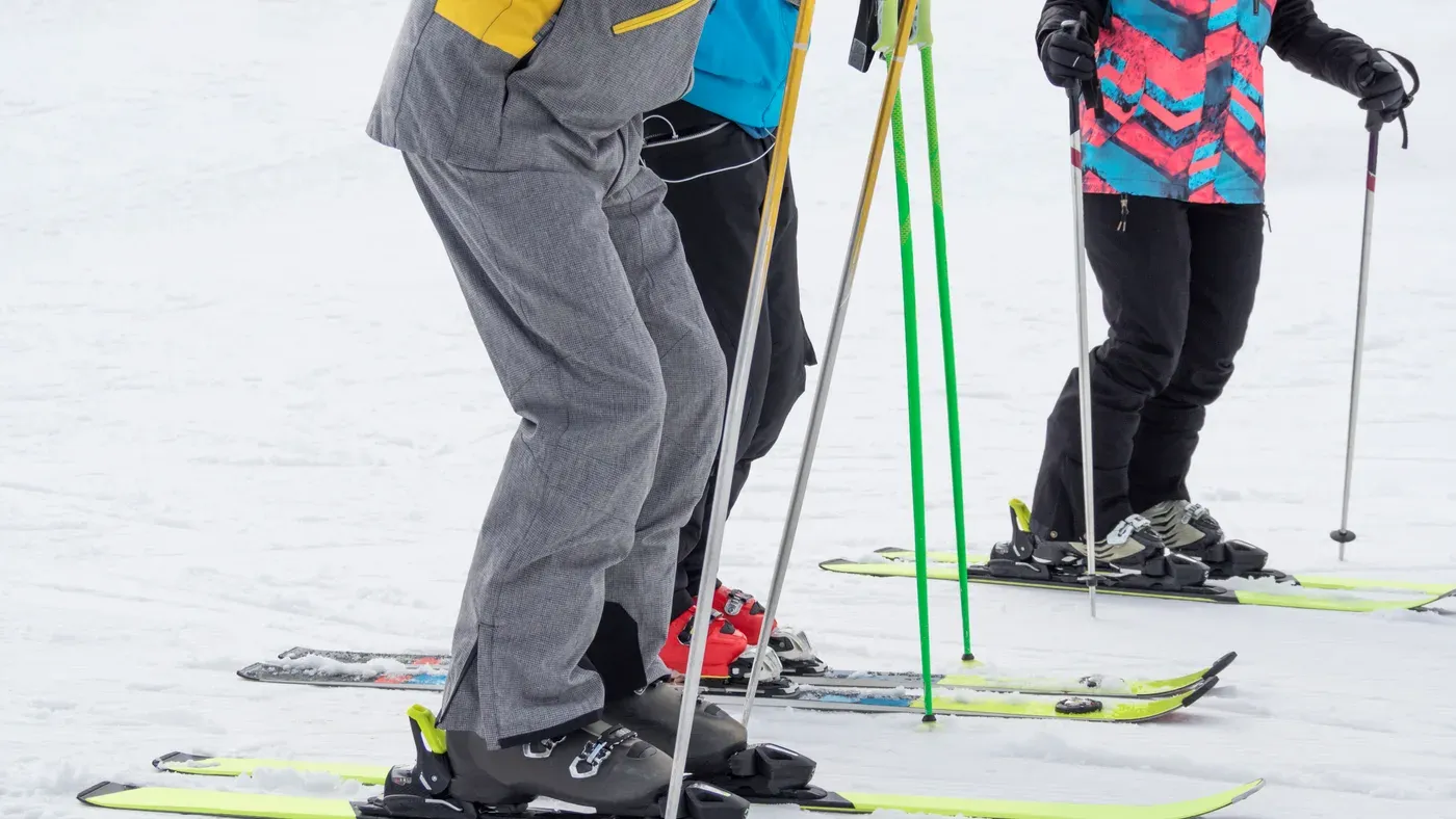 Närbild på tre alpinåkares ben, skidor och stavar
