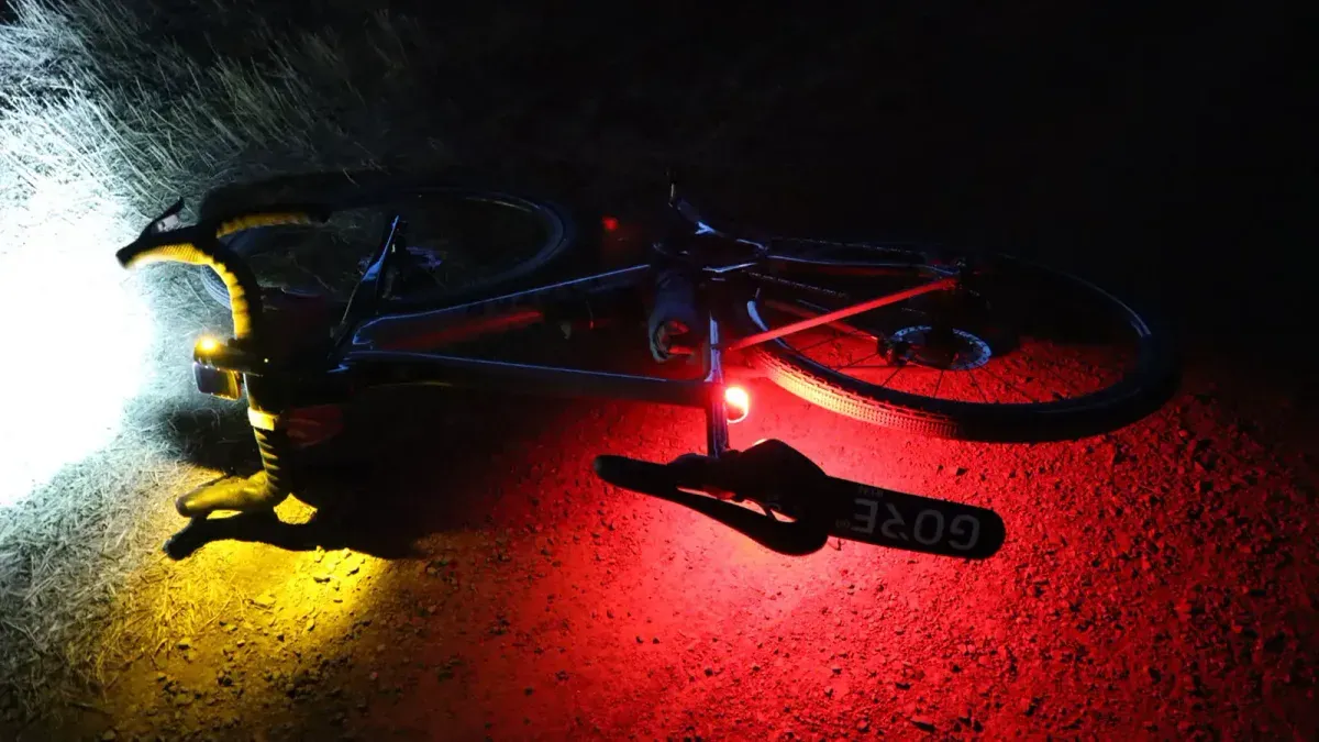 Cykel liggande i mörker med tända lyktor i rött och gult