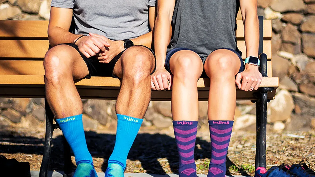 Två par ben med Injinji-tåstrumpor i olika färger på bänk