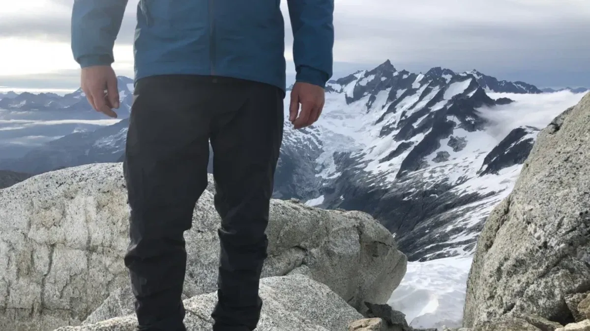 Man i mörka skalbyxor på klippa med glaciärvy