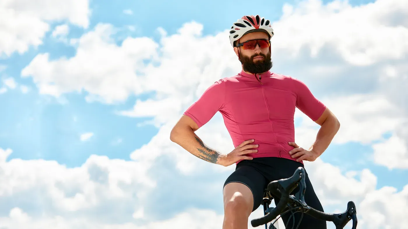 Cyklist i rosa cykeltröja poserar med händerna på höften
