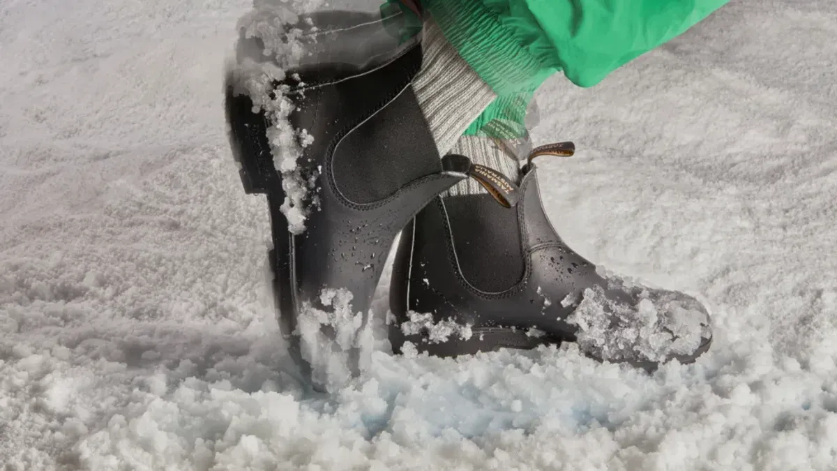 Svarta stövlar och gröna byxben i snö