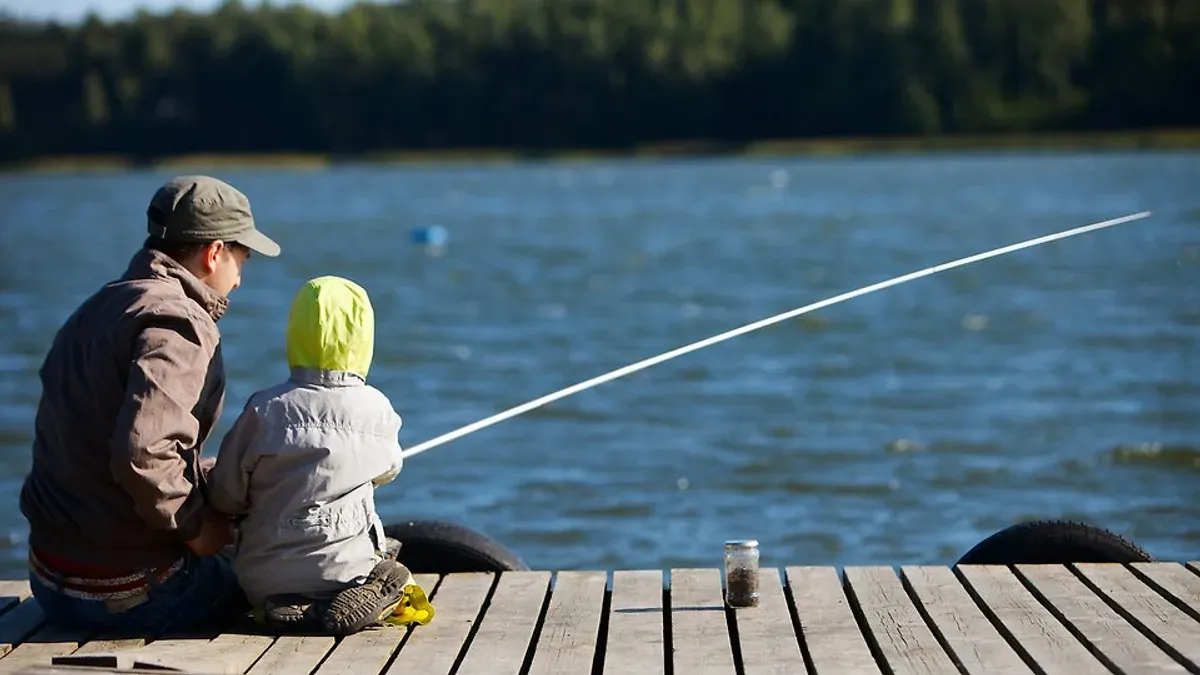 Vuxen och barn fiskar med spö från brygga