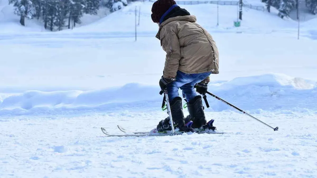 Barn åker skidor i brun jacka sett bakifrån