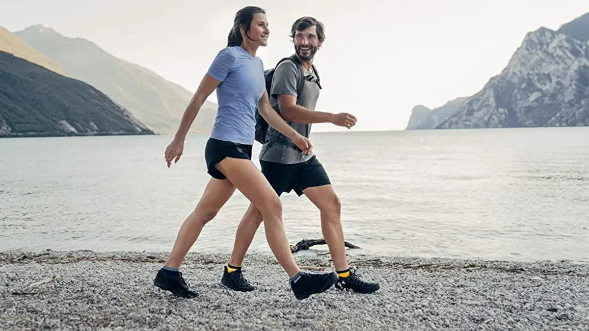Par som går längs strand i shorts och korta strumpor