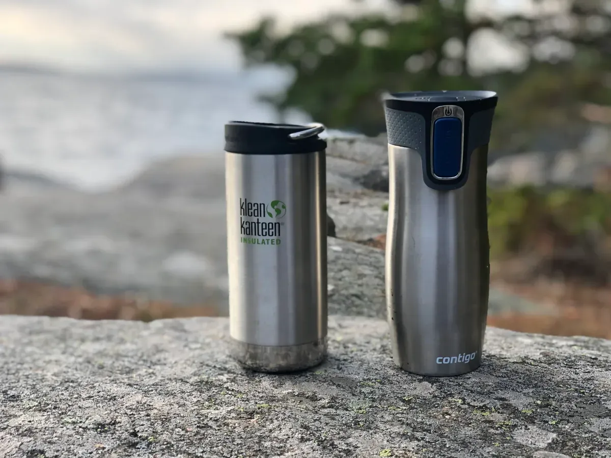 Två stål-termosmuggar på klippa vid havet
