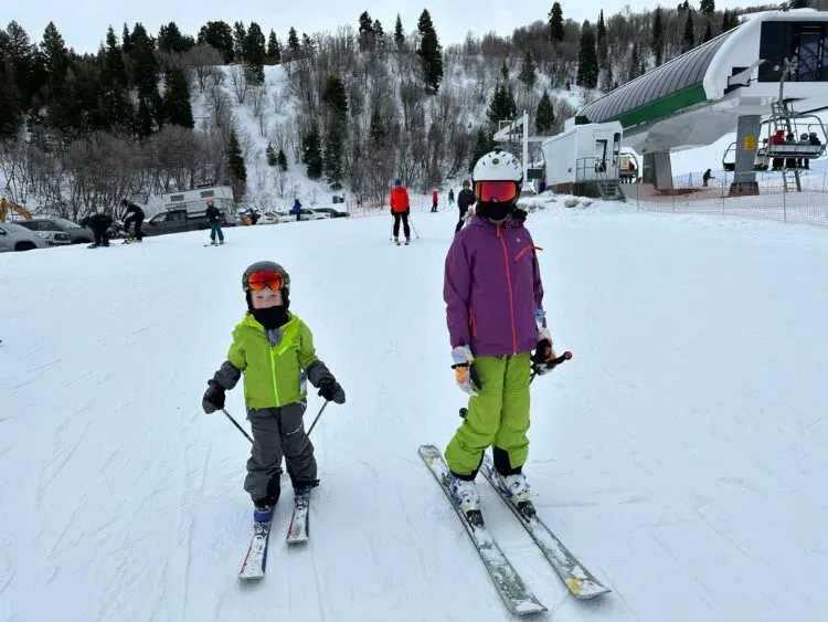 Två barn på skidor vid liftbacke i skidbyn