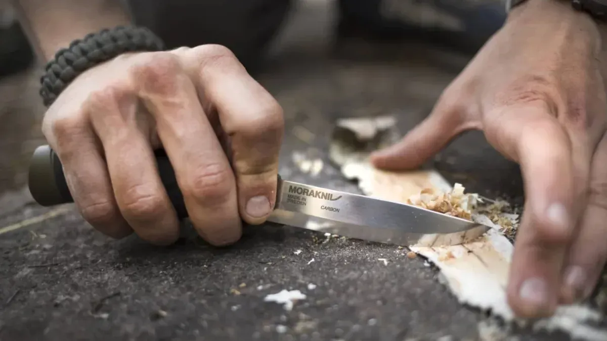 Händer tälgar näver med Moraknivens klinga