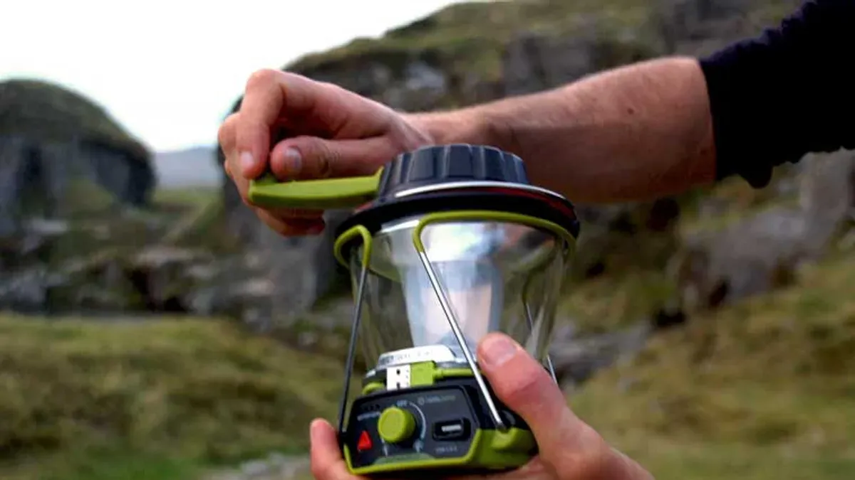 Händer skruvar ihop grön campinglampa utomhus