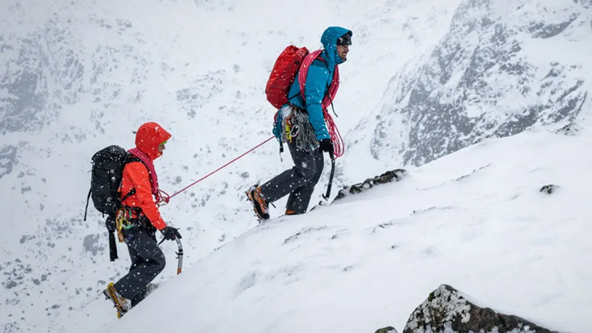 Två bergsklättrare i stegjärn på snötäckt sluttning