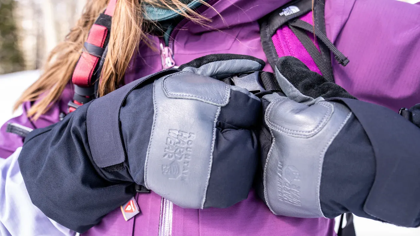Knutna nävar i grå vinterhandskar märkta Mountain Hardwear