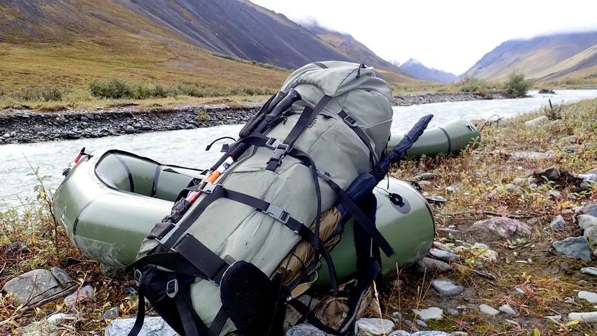 Grön jaktryggsäck fastspänd på packflotte vid fjällälv