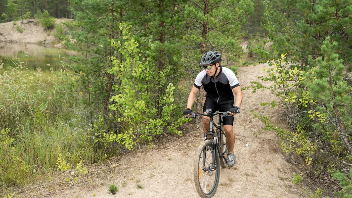 Cyklist i svartvit cykeltröja kör mountainbike på skogsstig