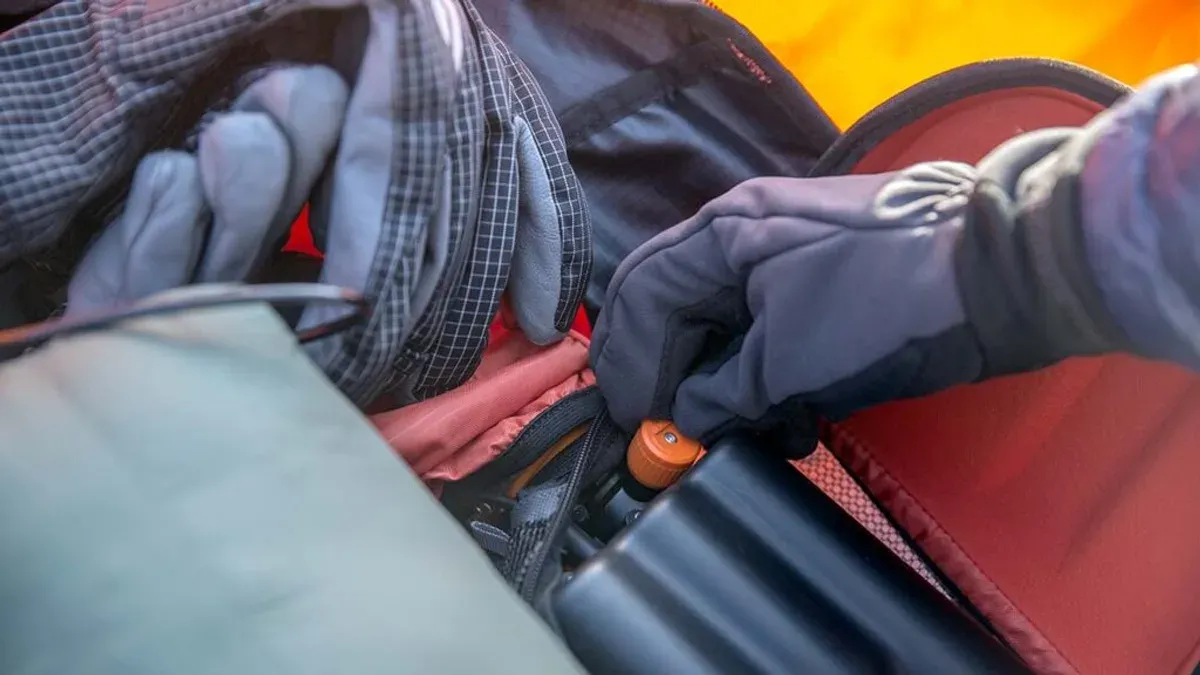 Handske vrider på ventil i öppnad lavinryggsäck