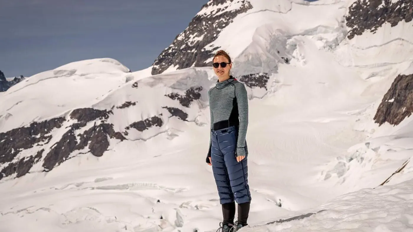 Kvinna i dunbyxor och solglasögon på glaciär