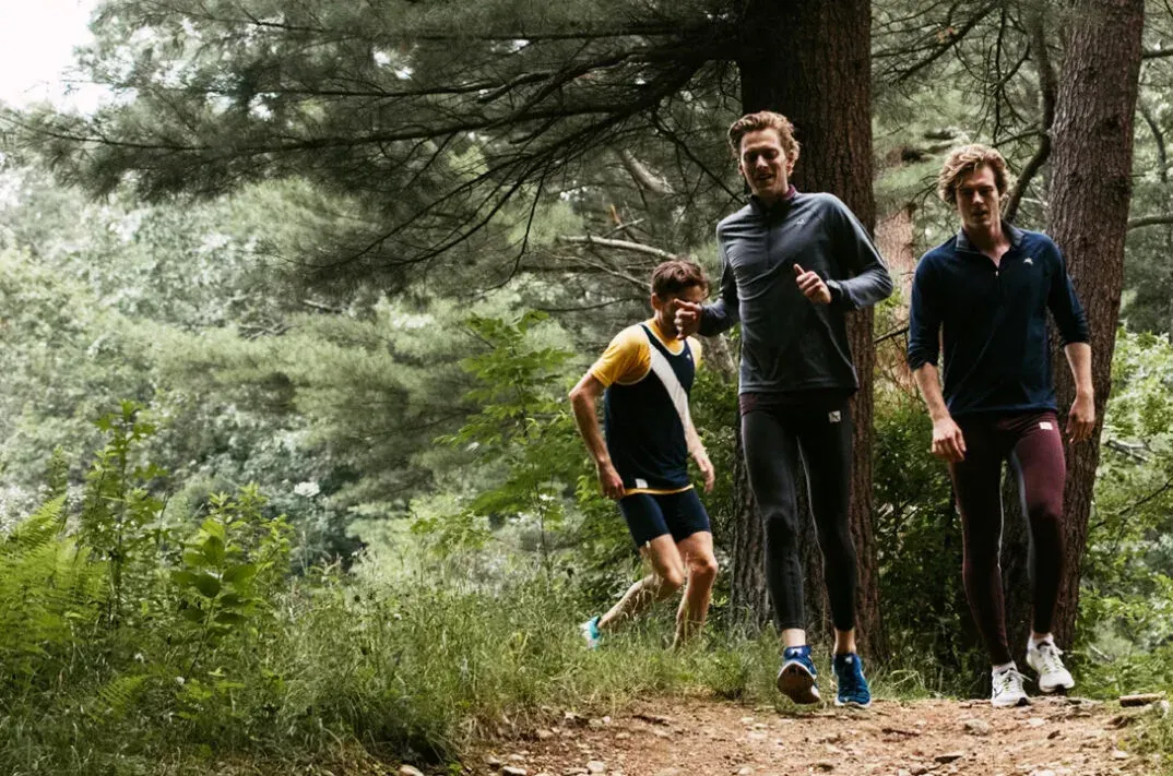 Tre män joggar tillsammans på skogsstig