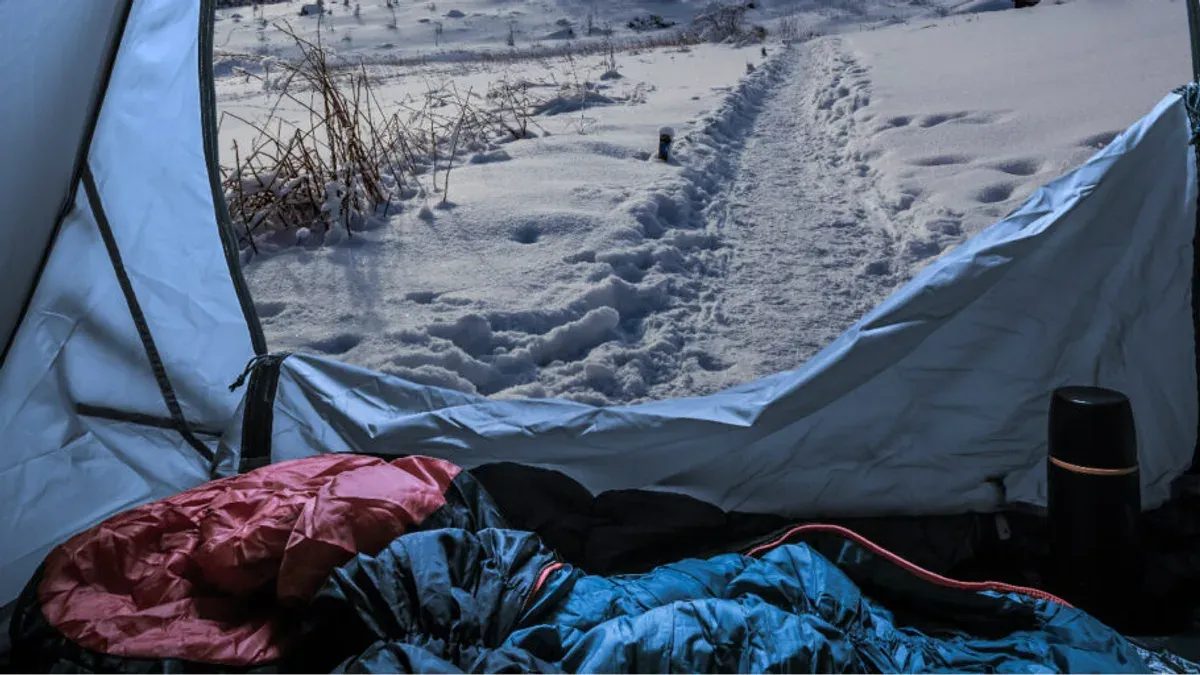 Sovsäckar i tältöppning med utsikt över snöig stig