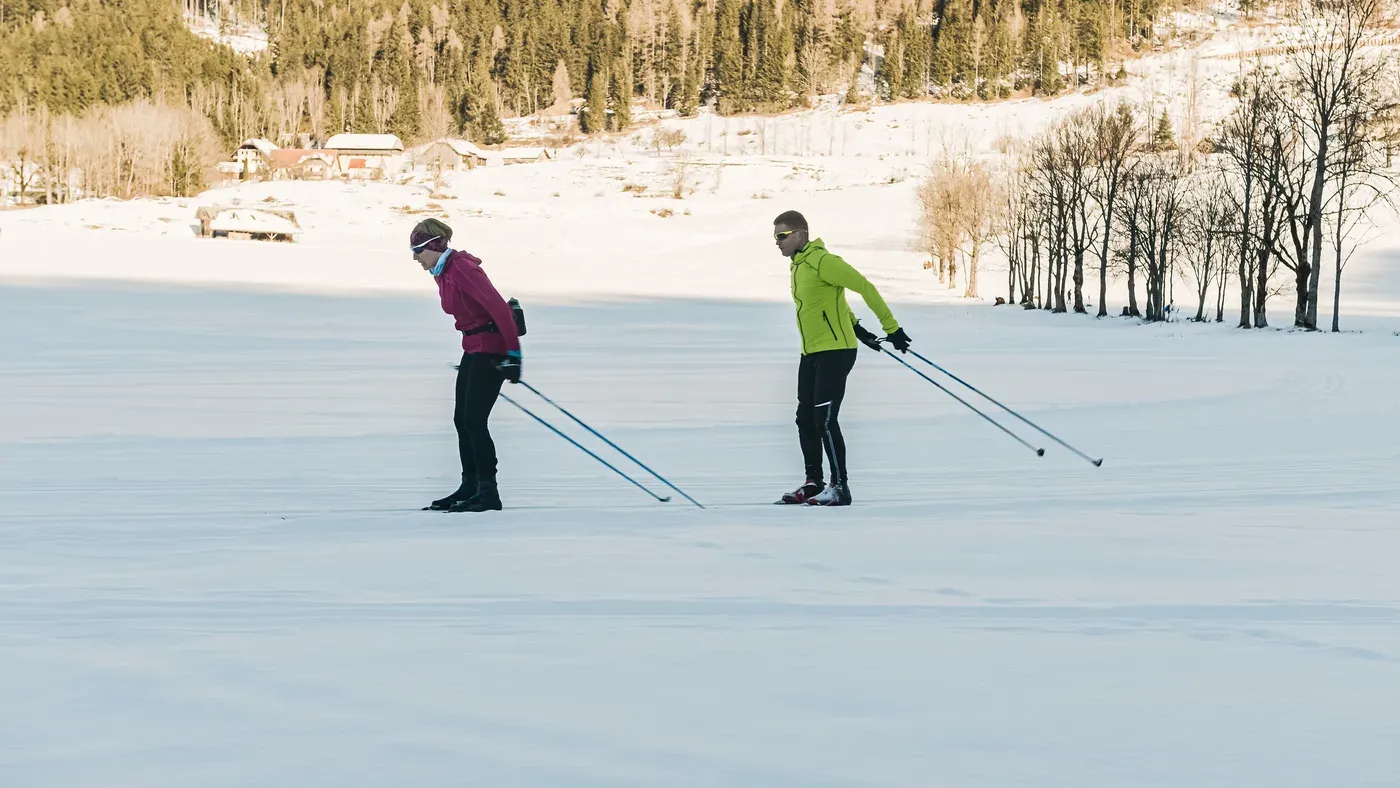Två längdskidåkare med stavar mot solnedgång på fjället